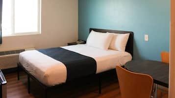 A single bed with a black frame, white bedding, and a blue wall.