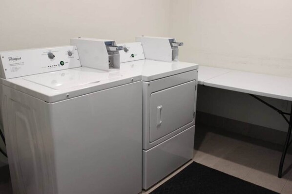 A compact, modern laundry room with two front-loading washing machines and a small storage cabinet.