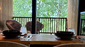 A dining area with a table set for two, a view of trees through large windows, and a wooden ceiling. - Refuxio da Carballeira - Cabin 2 (ideal for couples) (Rebordelo (San Martiño))