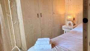 A wooden room with a bed, a wardrobe, and a nightstand with a lamp. - Refuxio da Carballeira - Cabin 2 (ideal for couples) (Rebordelo (San Martiño))