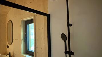 A bathroom with a wooden ceiling, a window, a mirror, and a shower with a black stand.