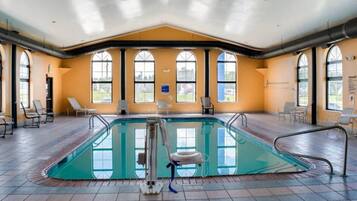 Una piscina interior amb parets de vidre transparent, diverses finestres i gandules.