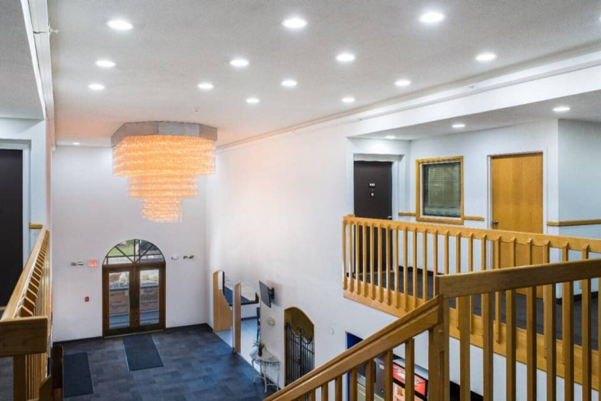 Un vestíbulo de hotel con una escalera, un candelabro y vistas al exterior.