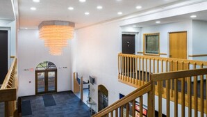 Un vestíbulo de hotel con una escalera, un candelabro y vistas al exterior.