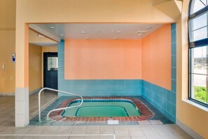Una piscina con borde de azulejos, baranda metálica y vistas al exterior a través de una ventana.