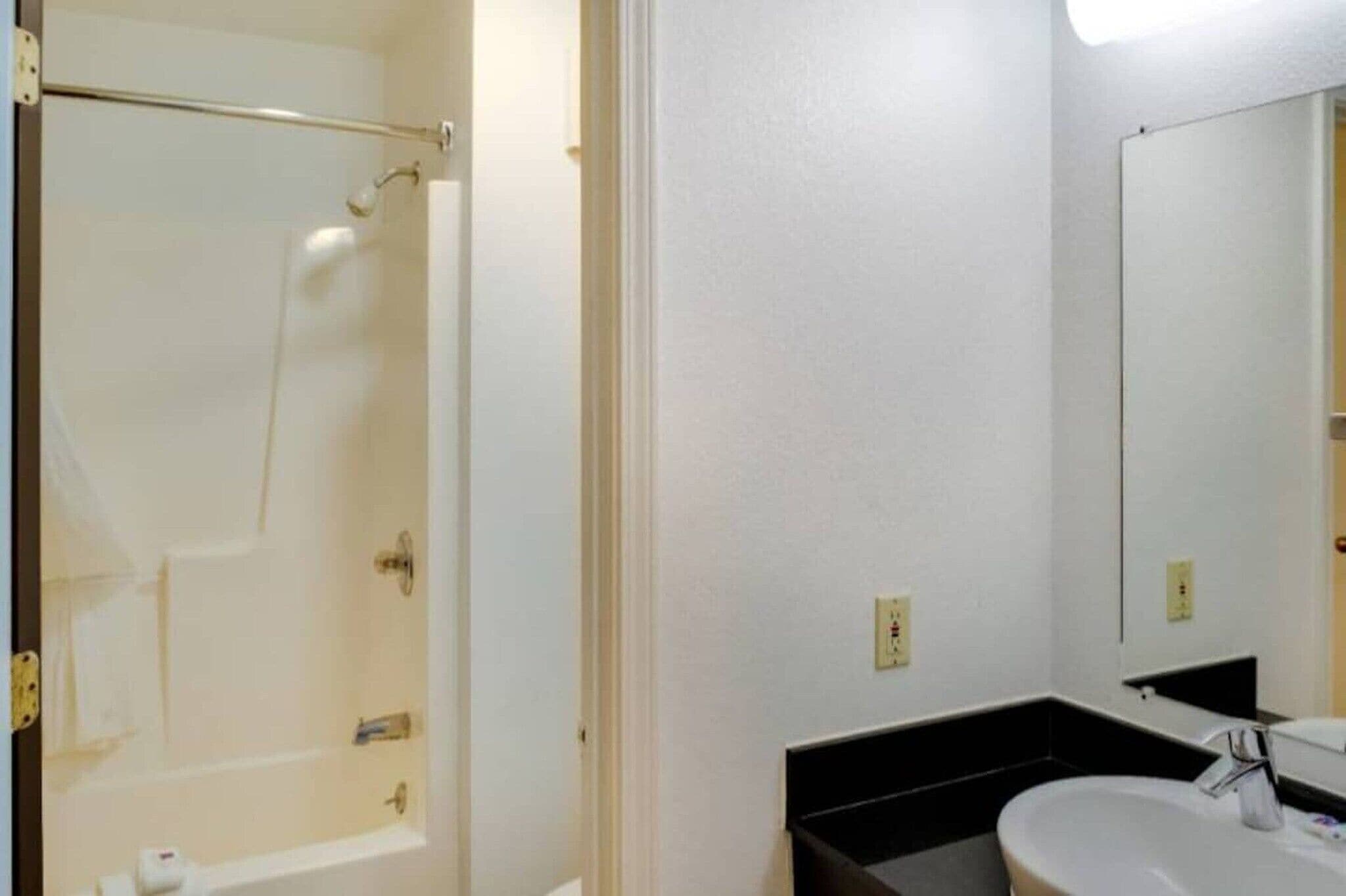A bathroom with a bathtub, a sink, and a mirror.
