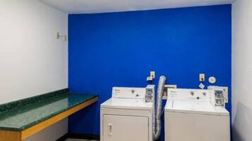 A laundry room with two front-loading washing machines, a green countertop, and a blue wall.