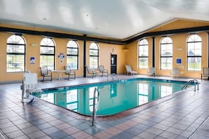 A large indoor swimming pool with multiple lounge chairs and a changing room.