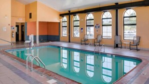A swimming pool with a tiled deck, a lifeguard chair, and a seating area with tables and chairs.