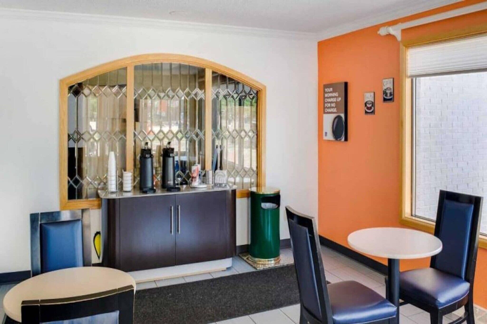 A room with a counter, chairs, a trash bin, and a window with a view.