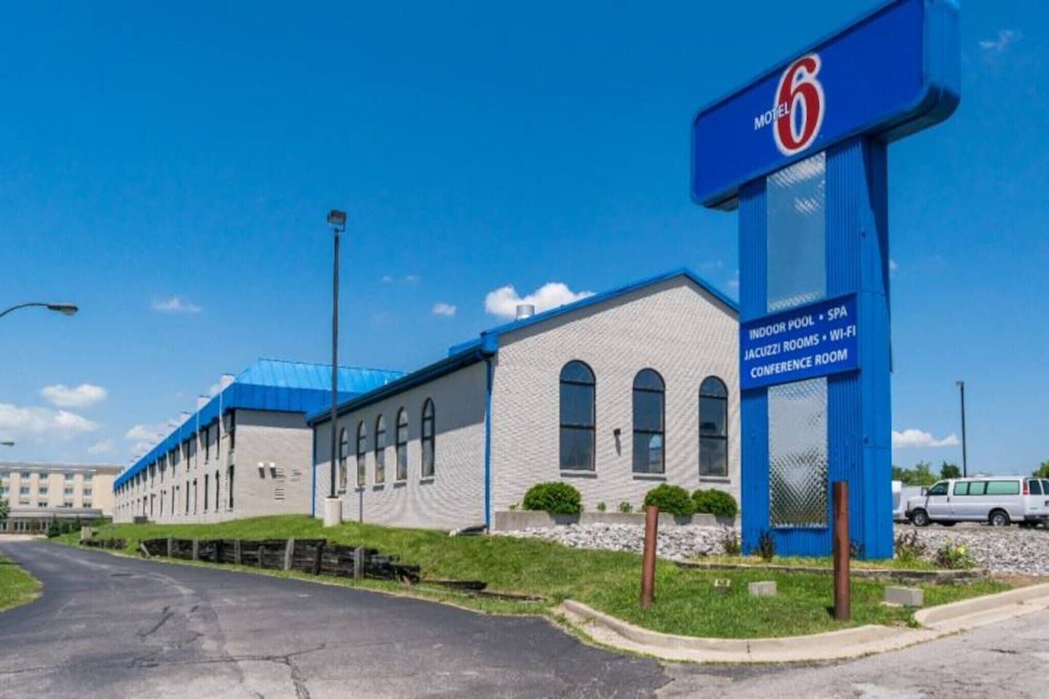 A motel with a prominent '6' sign, featuring amenities like an indoor pool, spa, jacuzzi rooms, Wi-Fi, and a conference room.