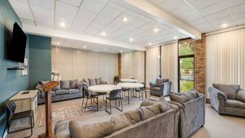 A spacious lounge area with sofas, a coffee table, and a TV mounted on the wall.