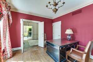 A room with a wooden floor, a desk with drawers, a chair, a lamp, and a door leading to another room. - 3 Mi to Dtwn! Grand Goldsboro Getaway (Goldsboro)