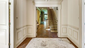 Un pasillo con alfombra blanca, una escalera con alfombra de estampado de leopardo y una puerta a la izquierda.