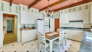 Una cocina con armarios blancos, una mesa de comedor con sillas, una araña y un salpicadero con diseño.