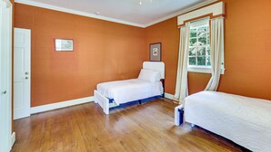 Una habitación con dos camas individuales, una ventana con cortinas, una puerta y una lámpara en el techo.