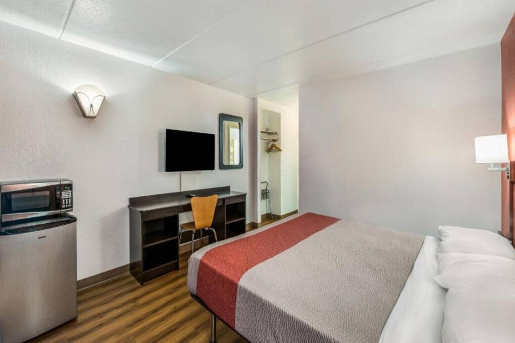 Ein Hotelzimmer mit einem Bett, einem Schreibtisch mit Stuhl, einem Fernseher, einer Mikrowelle und einem Kleiderschrank.