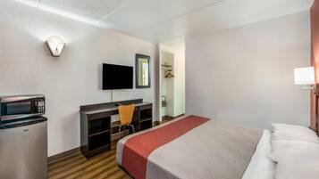 Ein Hotelzimmer mit einem Bett, einem Schreibtisch mit Stuhl, einem Fernseher, einer Mikrowelle und einem Kleiderschrank.