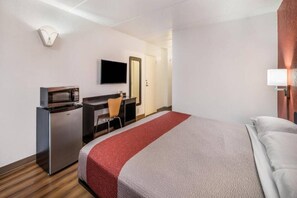 A hotel room with a bed, a desk, a television, and a microwave. - 1 King Bed | Non-Smoking (HENDERSON)