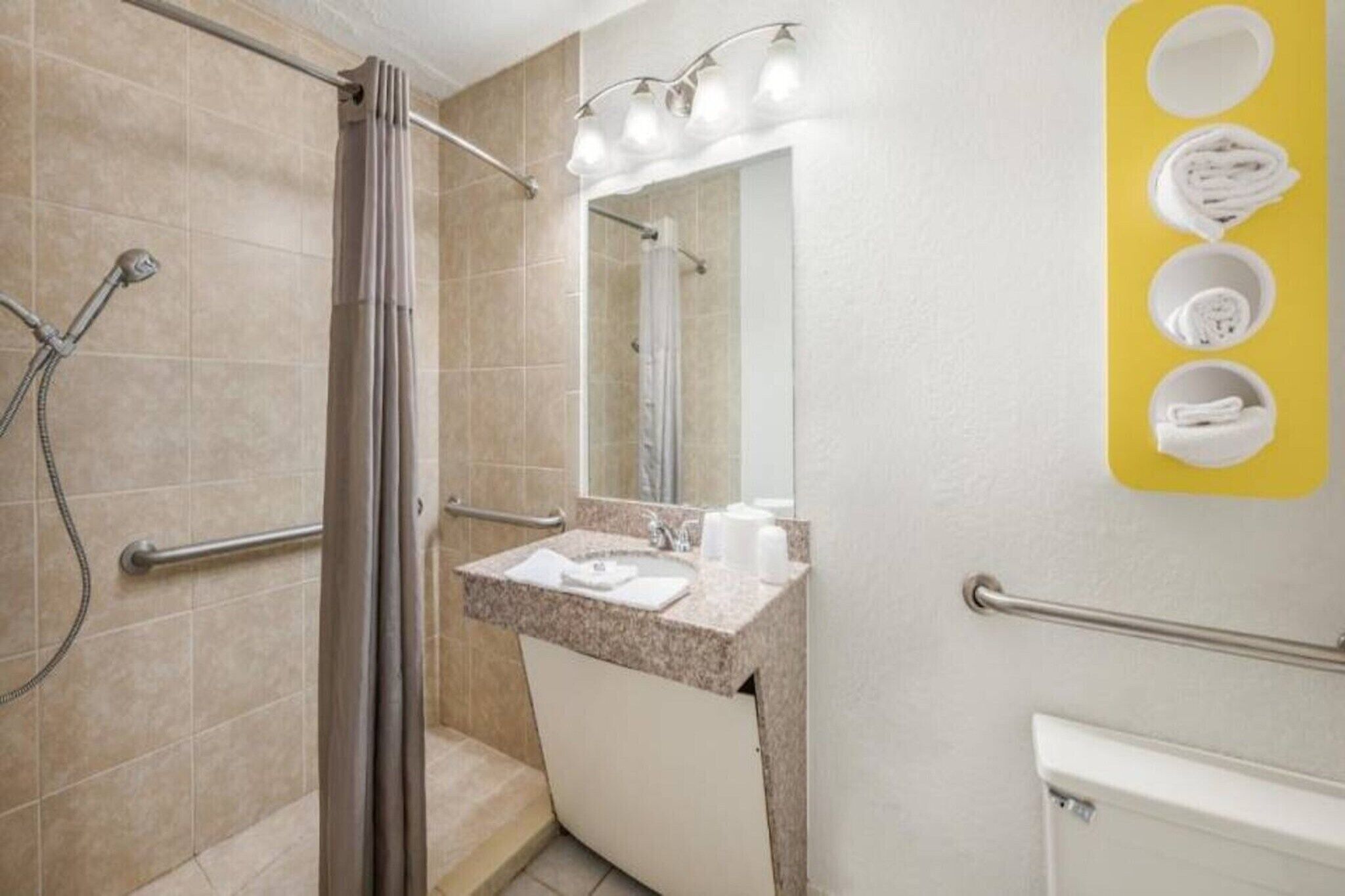 A bathroom with a shower, a sink with a mirror, and a towel rack.