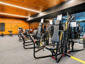 Une salle de sport équipée de divers appareils d’exercice, avec un plafond en bois et un sol recouvert de moquette.