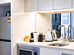 Eine moderne Küche mit Backofen, einer Kaffeemaschine, einem Wasserkocher und einem Spülbecken mit Armatur.