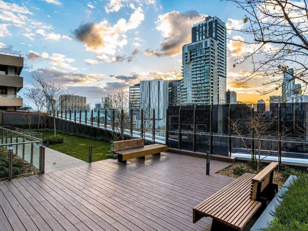Eine Dachterrasse mit Holzdeck, Bänken und Blick auf die Stadtlandschaft.
