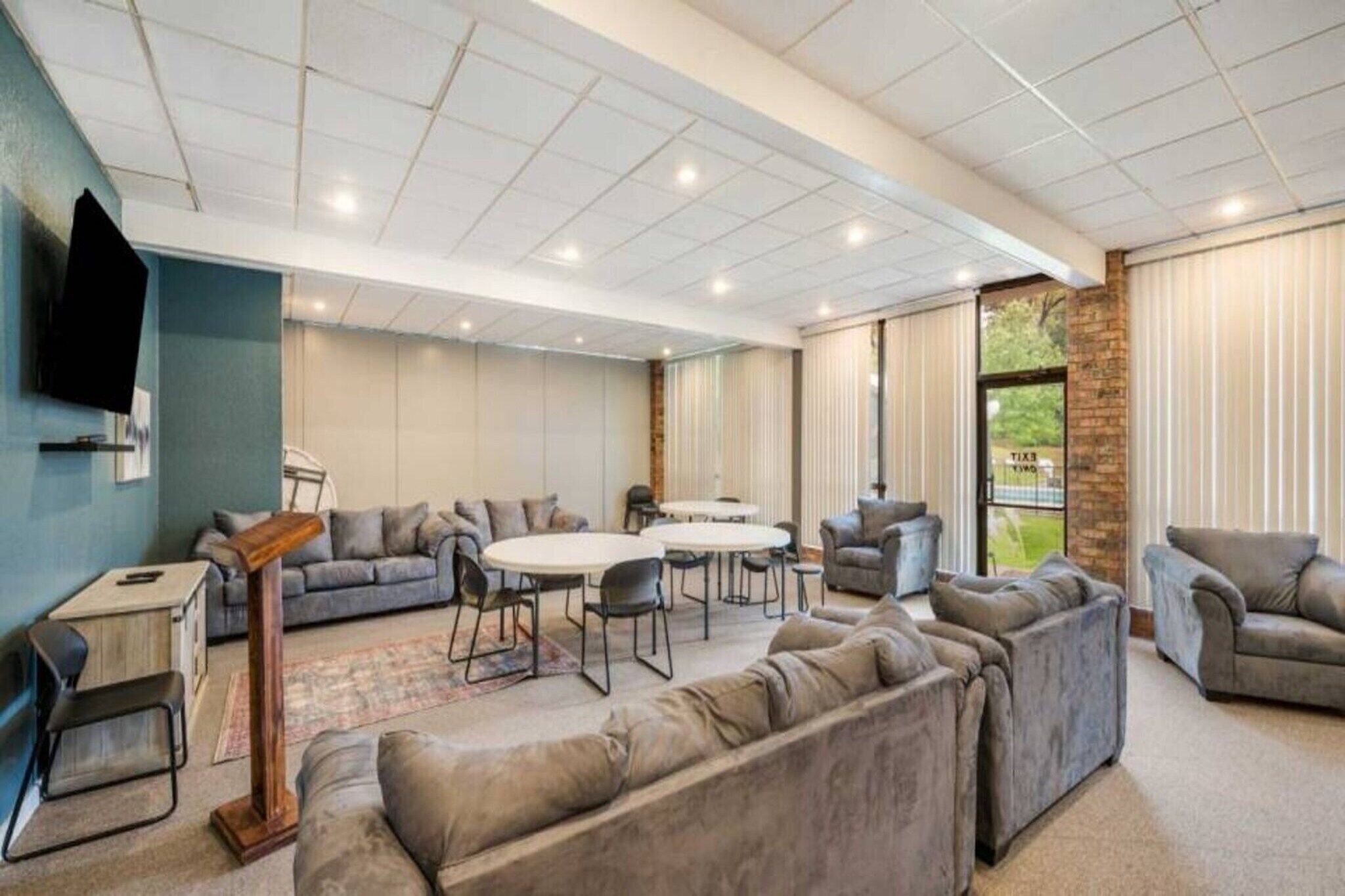 A spacious lounge area with sofas, a coffee table, and a TV mounted on the wall.