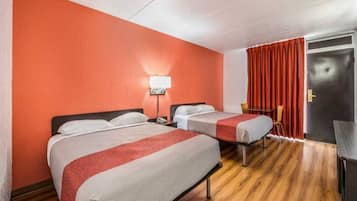 A hotel room with two beds, a desk, a chair, and a door.