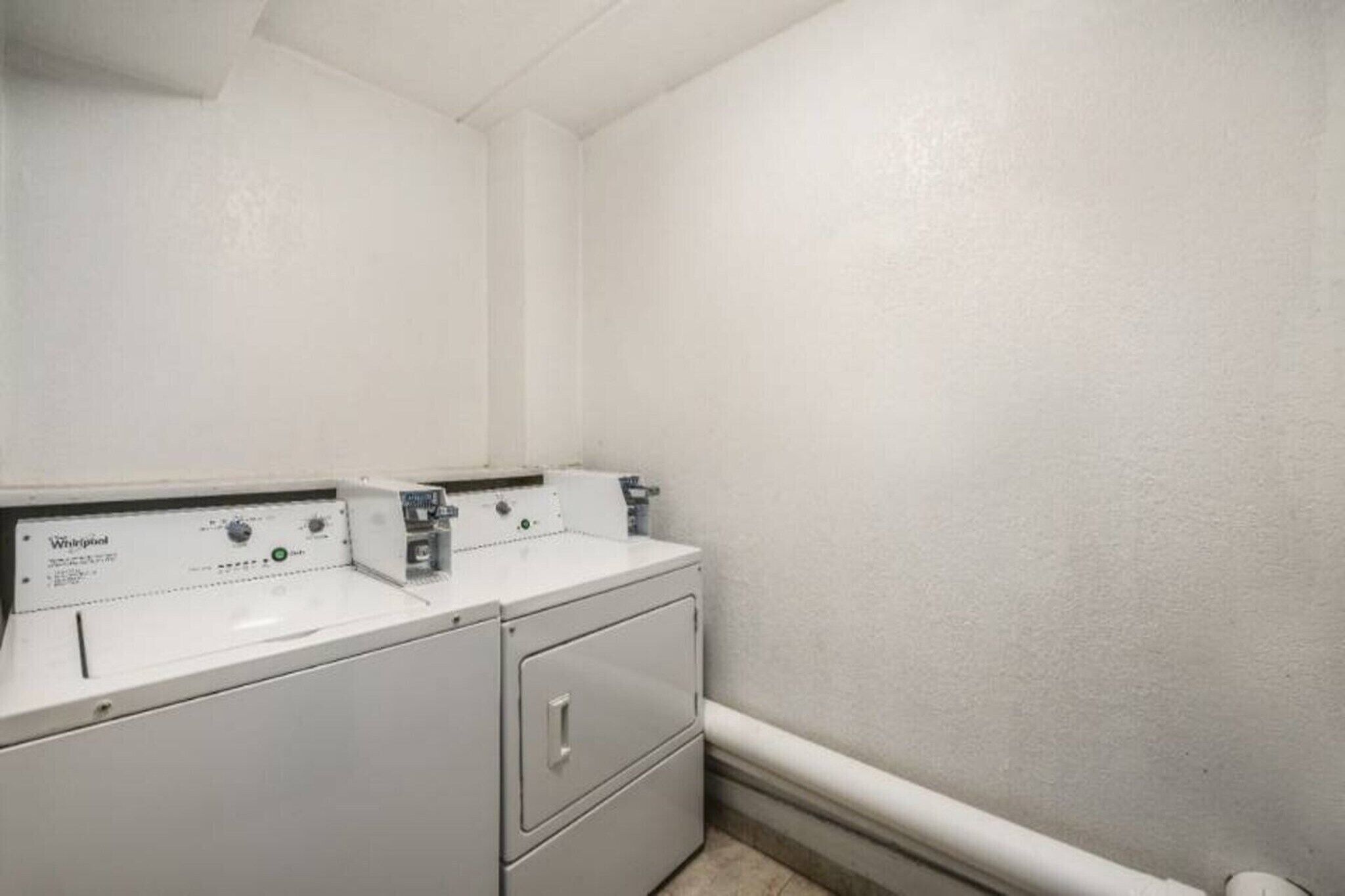 A laundry room with two Whirlpool washers and a dryer.