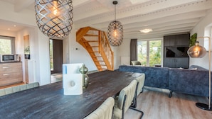 Eine moderne Küche mit dunkler Arbeitsplatte, einer Holztreppe und Pendelleuchten.