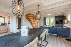 Eine moderne Küche mit dunkler Arbeitsplatte, einer Holztreppe und Pendelleuchten.