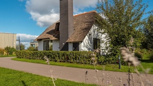 Ein Haus mit Strohdach, Schornstein und weißer Fassade.
