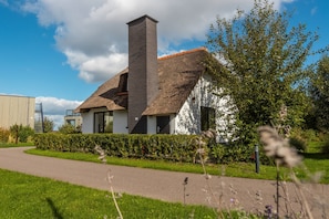 Ein Haus mit Strohdach, Schornstein und weißer Fassade.