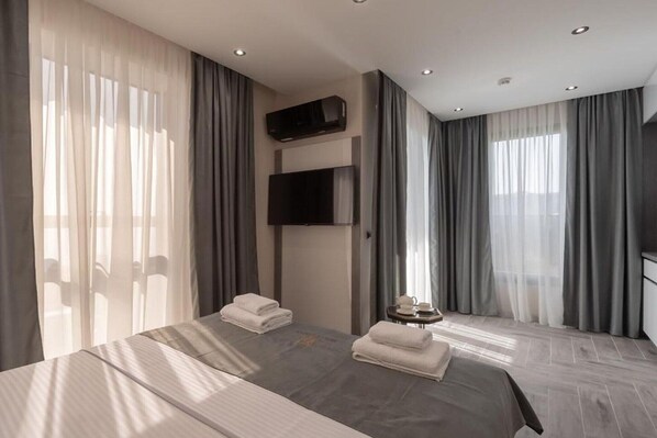 A hotel room with a large bed, a flat-screen TV mounted on the wall, and a small table with a tray.