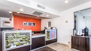 Un espace d’accueil d’hôtel comprenant un comptoir, un coin café et un grand miroir.