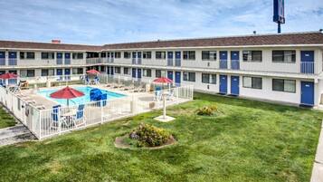 A motel with a swimming pool, multiple balconies, and a well-maintained lawn.