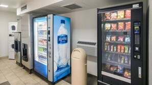 Un espace équipé d’un distributeur automatique de boissons et d’un autre distributeur automatique de collations.