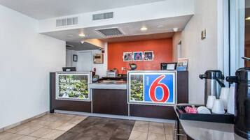 A hotel reception area with a counter, a coffee machine, and a sign for the number 6.