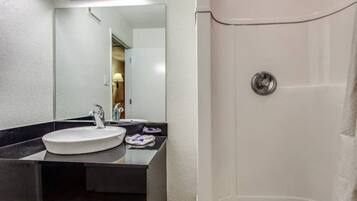 A bathroom with a sink, mirror, and shower.