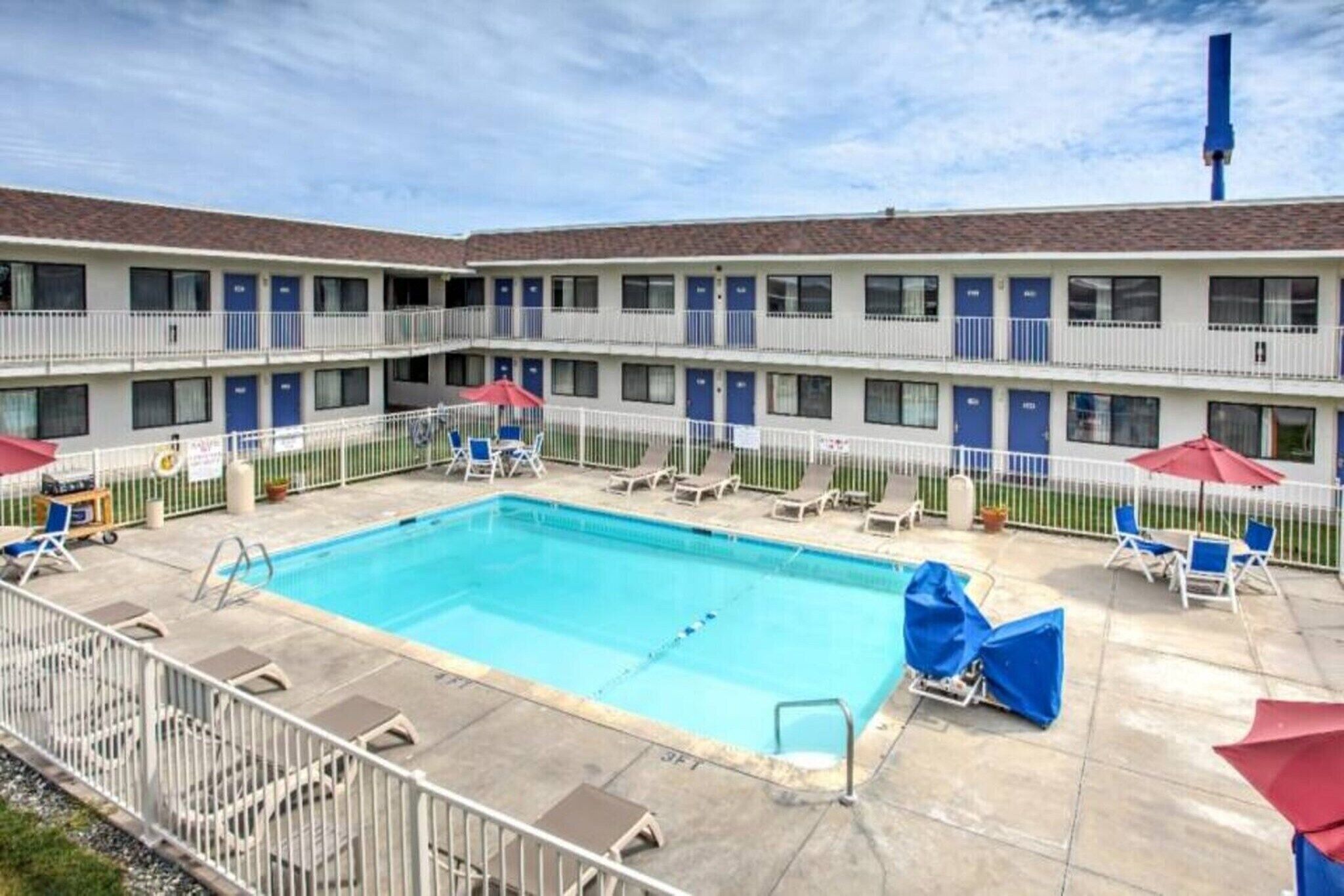 A hotel with a swimming pool, multiple balconies, and outdoor seating.