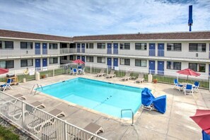 A hotel with a swimming pool, multiple balconies, and outdoor seating.