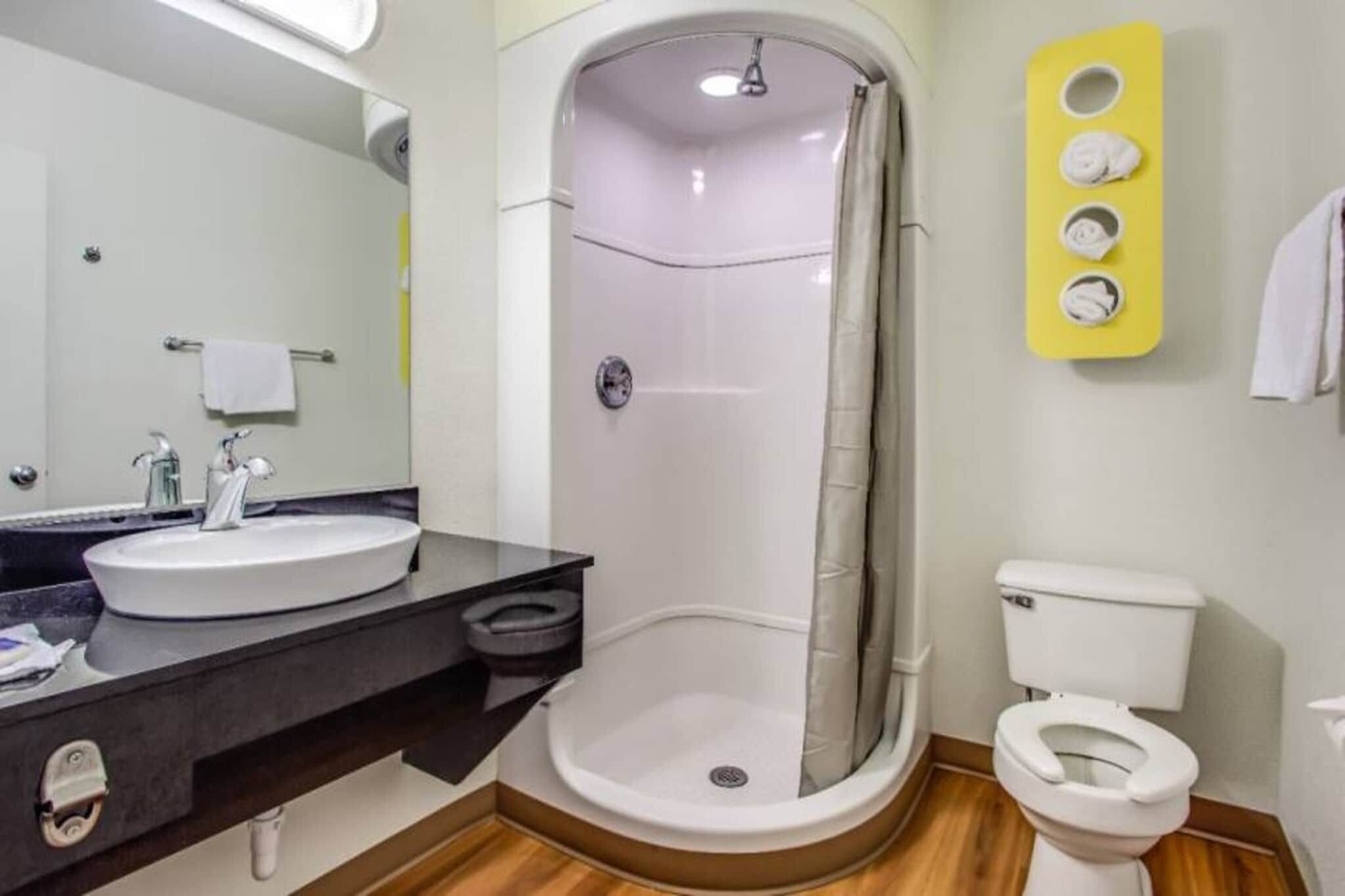 A bathroom with a shower, toilet, sink, and a mirror.