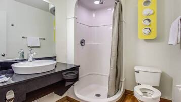 A bathroom with a shower, toilet, sink, and a mirror.