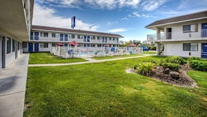 A motel with a swimming pool, multiple rooms, and a well-maintained lawn. - 1 Queen Bed | ADA/RI Shower/Non-Smoking (Williams)