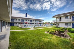 A motel with a swimming pool, multiple rooms, and a well-maintained lawn. - 1 Queen Bed | ADA/RI Shower/Non-Smoking (Williams)