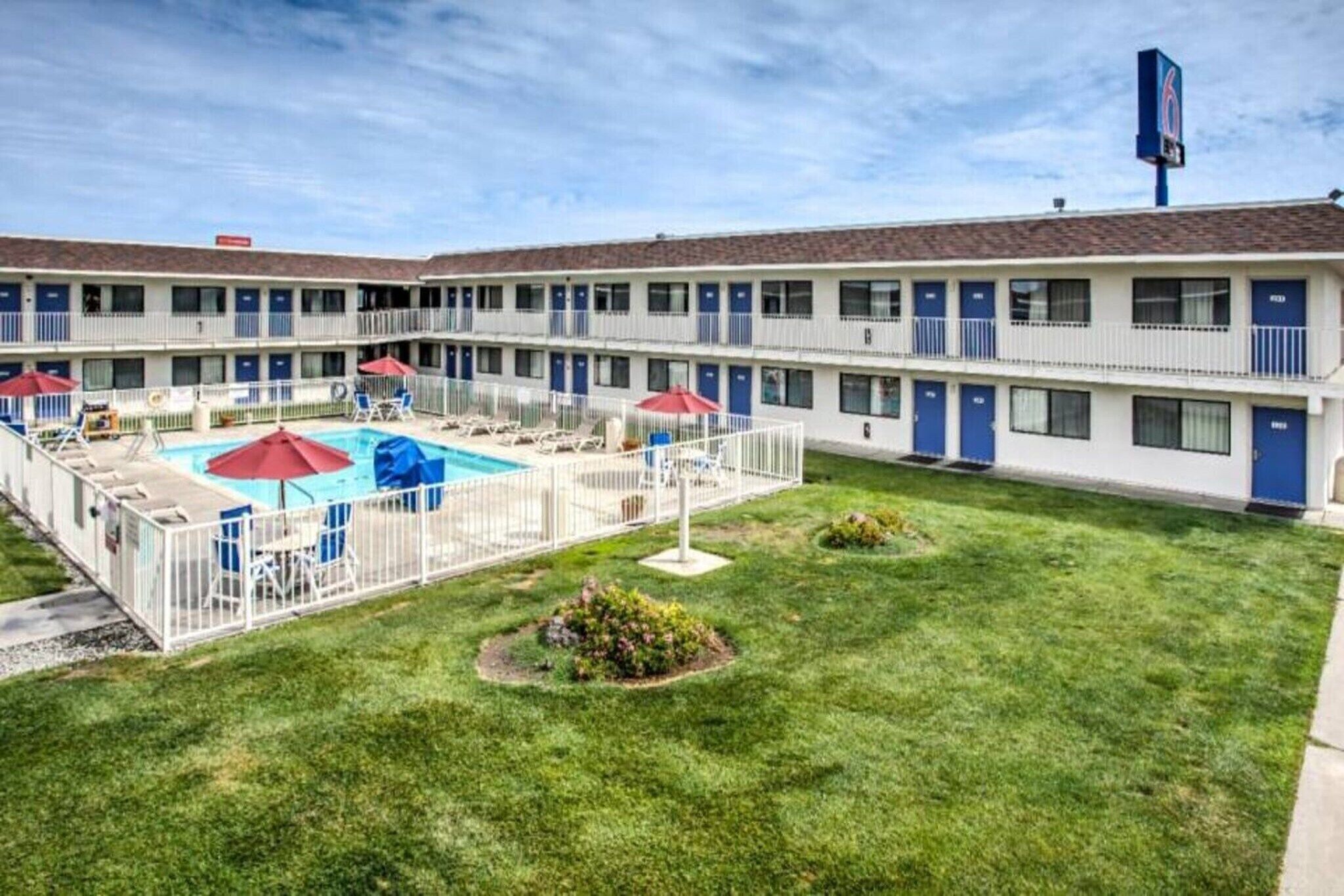 A motel with a swimming pool, multiple balconies, and a well-maintained lawn.