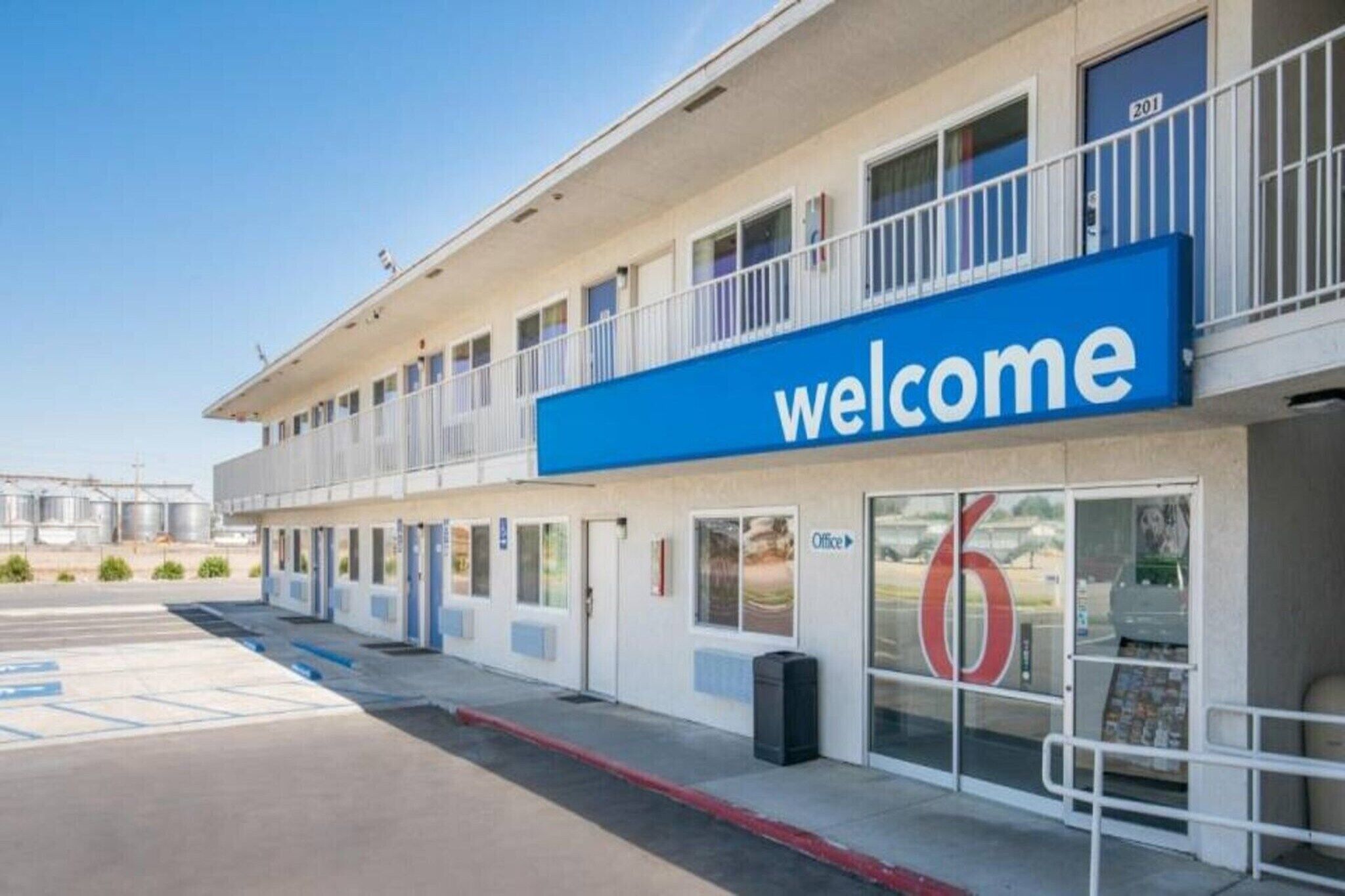 A motel with a prominent 'welcome' sign, a parking lot, and a building with multiple doors.
