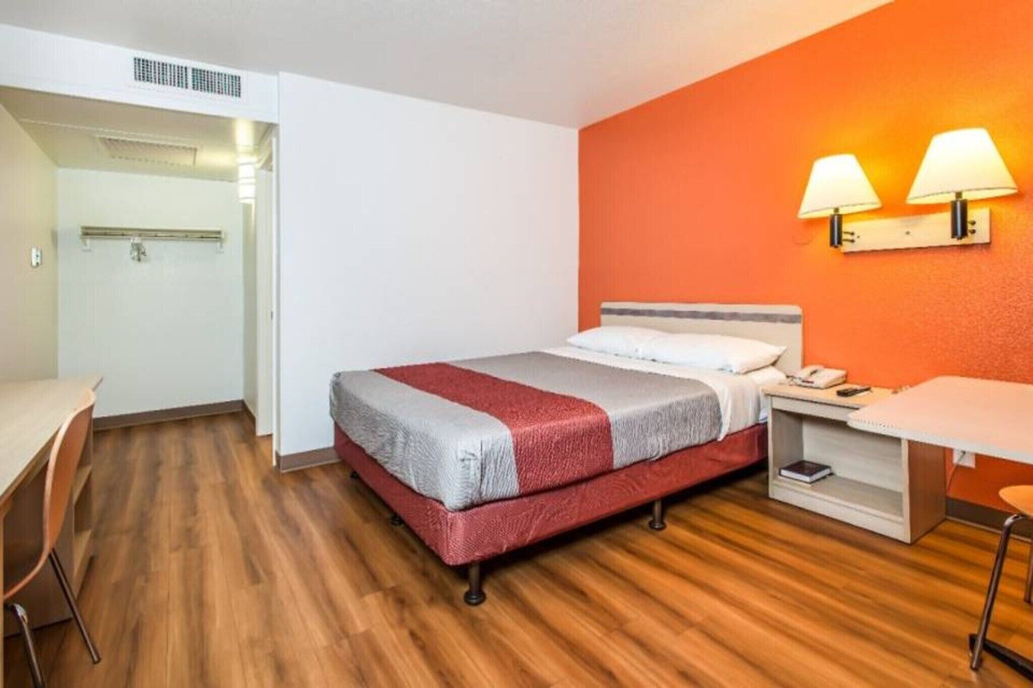 A hotel room with a bed, a desk, a chair, and a nightstand.