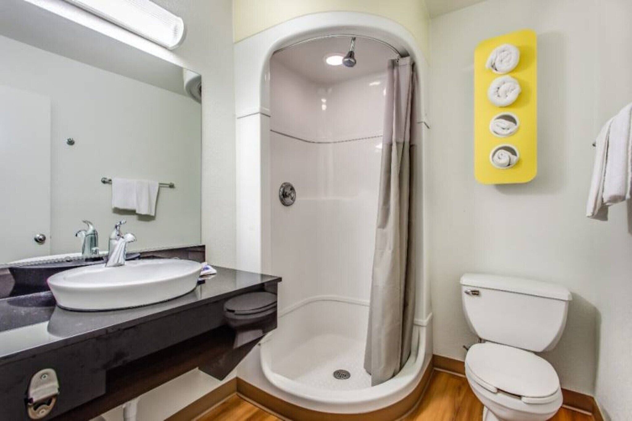 A bathroom with a shower, toilet, sink, and a mirror.
